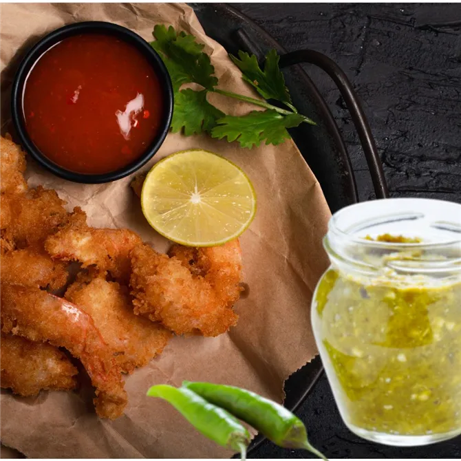 Platter of fried nibbles with cut lemon, a black bowl of tomato ketchup and a jar of green chillie sauce.