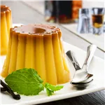 Bourbon Vanilla Pudding  on a white plate garnished with mint and dessert cutlery on side of plate.