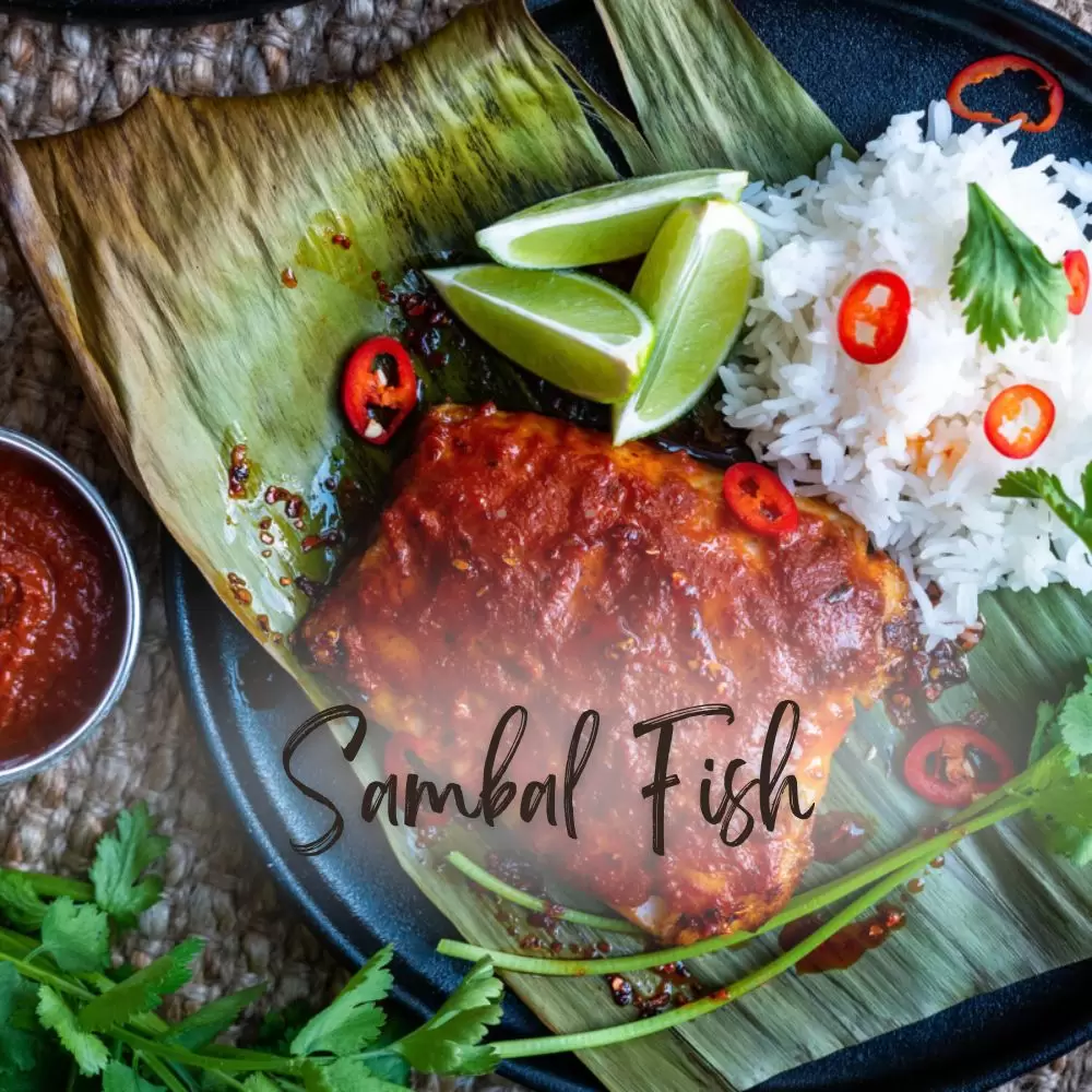 Sambal fish on a banana leaf with rice, lime wedges and fresh chilli